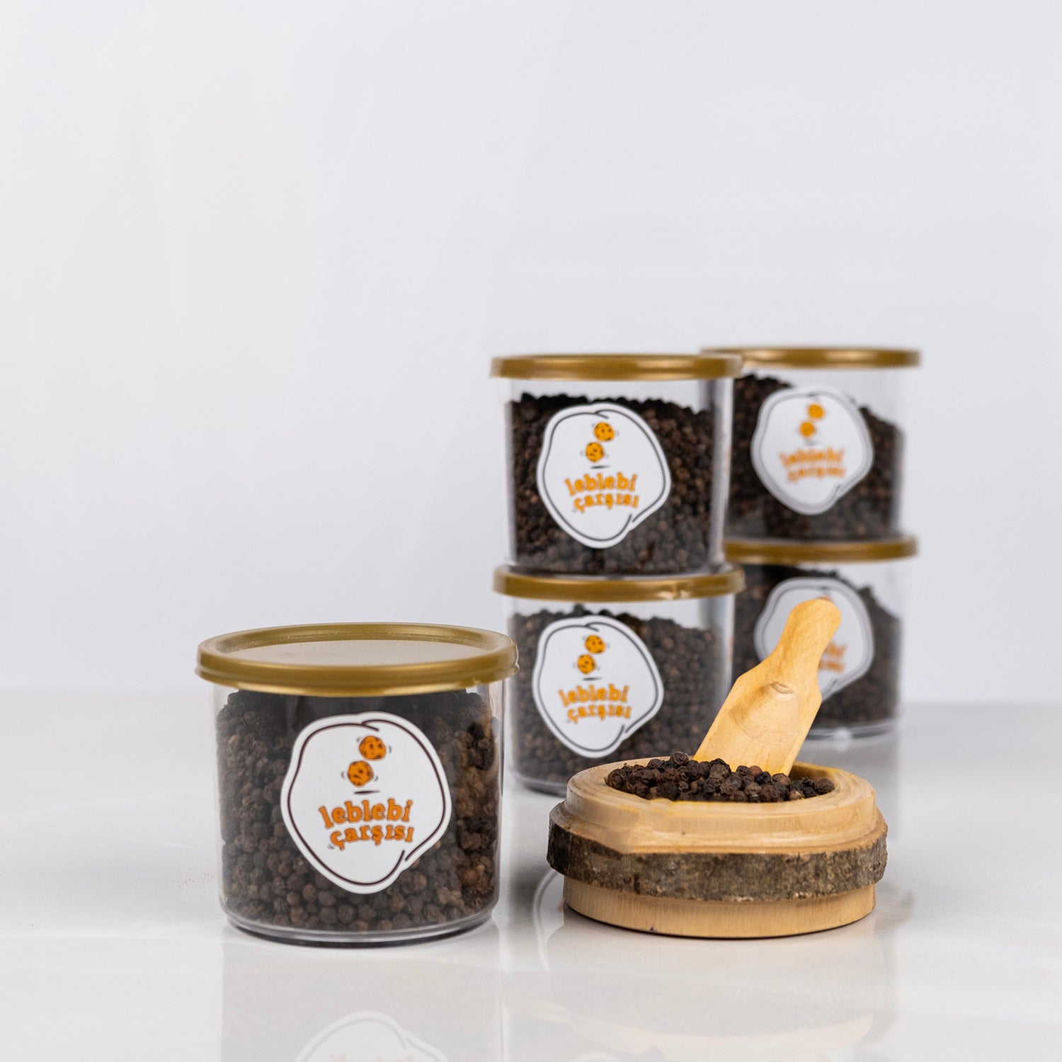 Doğal tane karabiber, iri taneli ve yoğun aromalı baharat ürünü olarak sade zeminde sunulmuş.