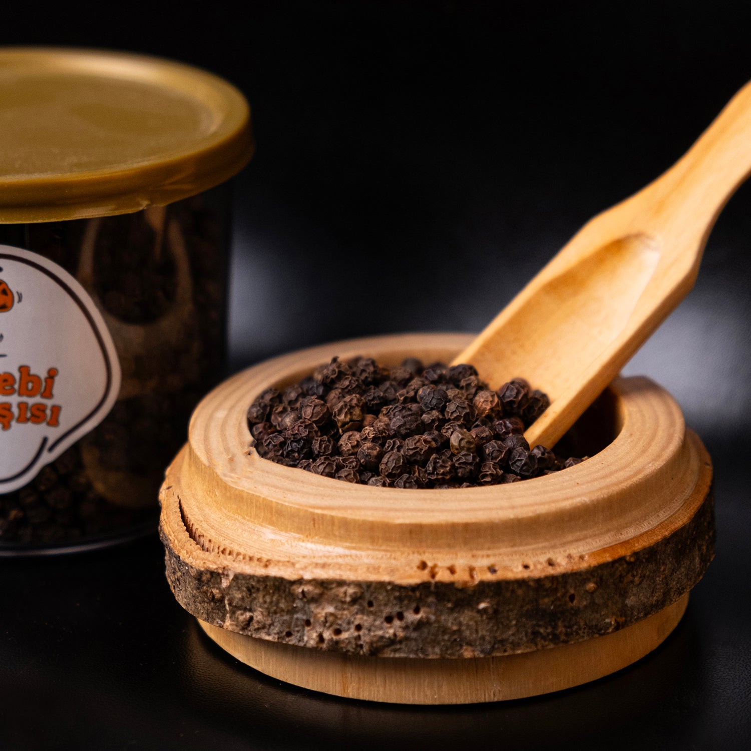 Doğal tane karabiber, iri taneli ve yoğun aromalı baharat ürünü olarak sade zeminde sunulmuş.